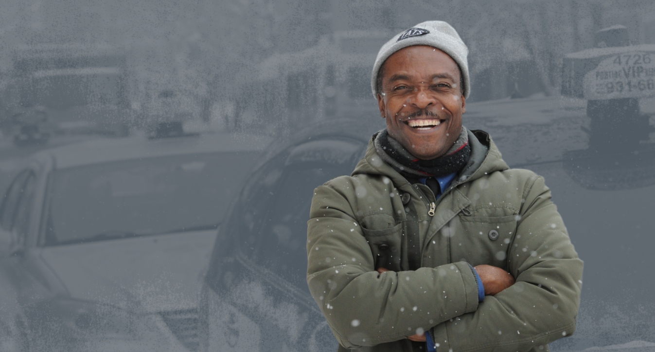 Smiling USW member in winter clothing in front of a taxi