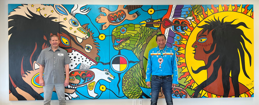 District 6 Director Myles Sullivan and Indigenous artist Philip Cote standing in front of a mural