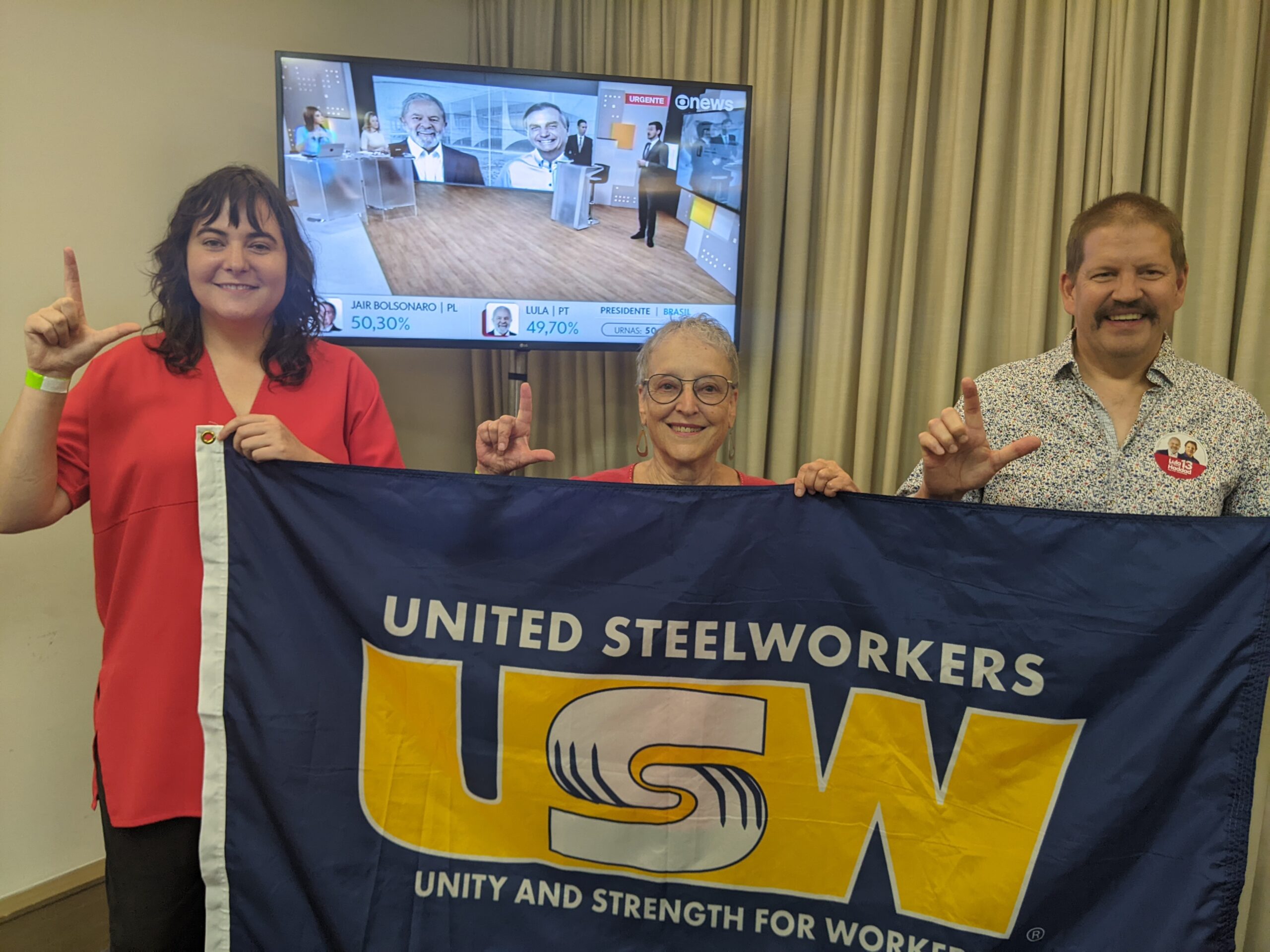 Three people standing, holding a blue United Steelworkers flag