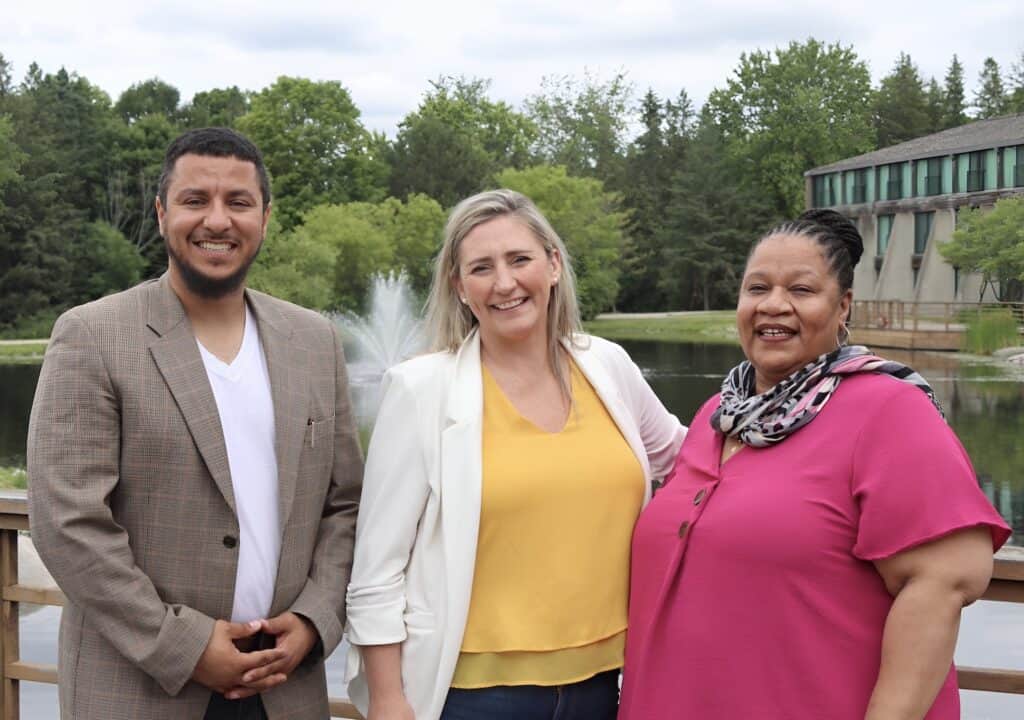 Three people standing side by side outdoors.