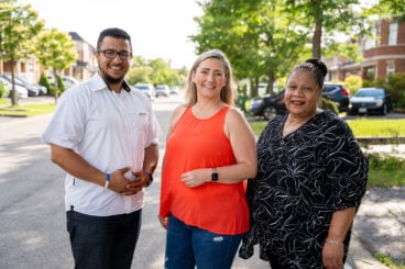 Three people standing side by side outdoors.
