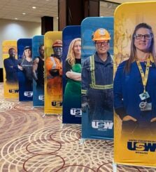 Image: a line-up of seven stand-up banners picturing members of the steelworkers union