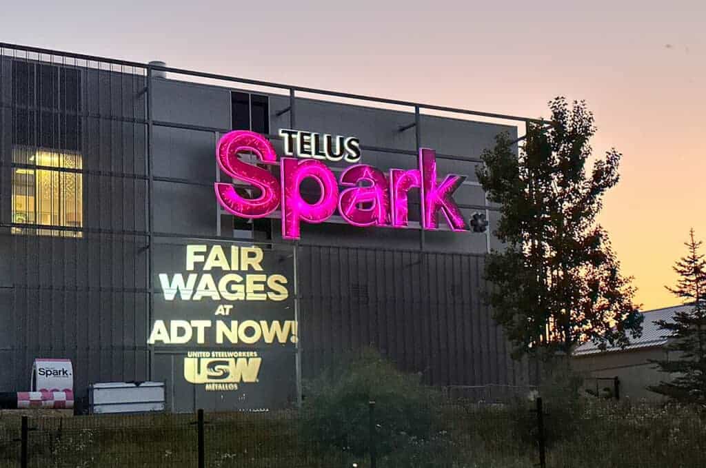 USW bat light shines "Fair Wages for ADT NOW!" on to the Telus Spark building.
