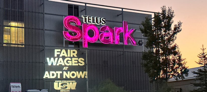 USW bat light shines "Fair Wages for ADT NOW!" on to the Telus Spark building.