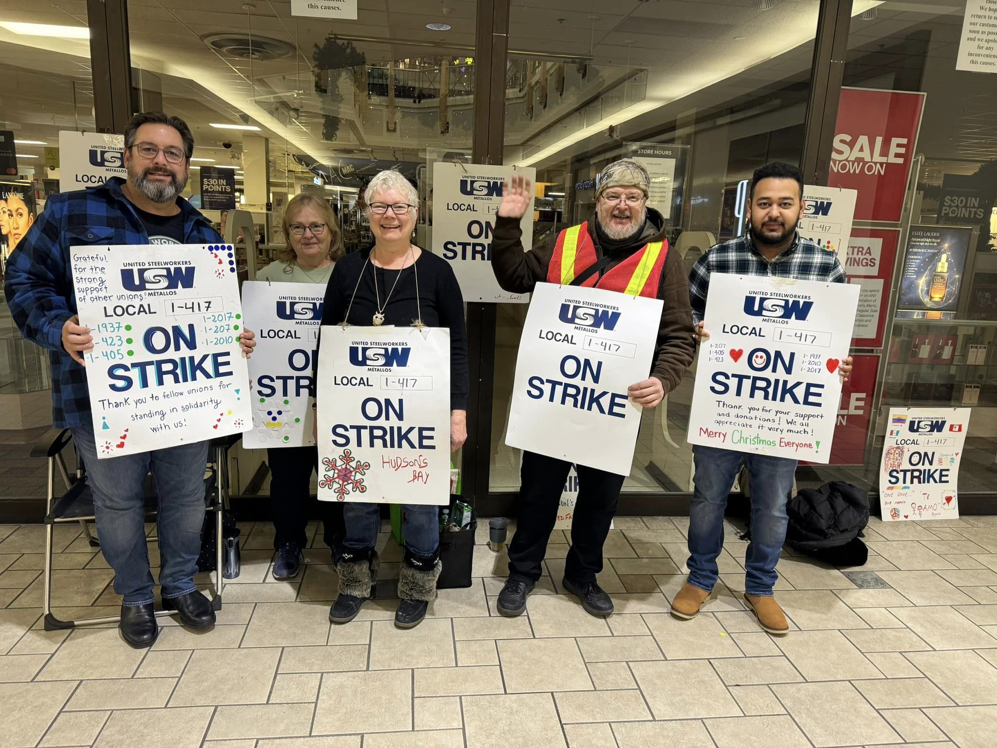 5 people holding "On Strike" signs at Hudson's Bay in Kamloops
