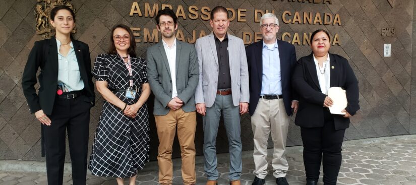 A photo of 6 people standing side by side in front of a the Embassy of Canada building in Mexico City.