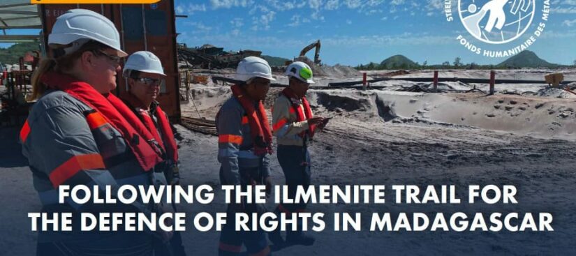 A photo of four people wearing satefy gear and walking in a mine. There are mining equipments in the background spread around and large sandy surface. There is text on the top of the photo saying STEELWORKERS HUMANITY FUND UPDATE - June 2024. More text at the very bottom saying: FOLLOWING THE ILMENITE TRAIL FOR THE DEFENCE OF RIGHTS IN MADAGASCAR