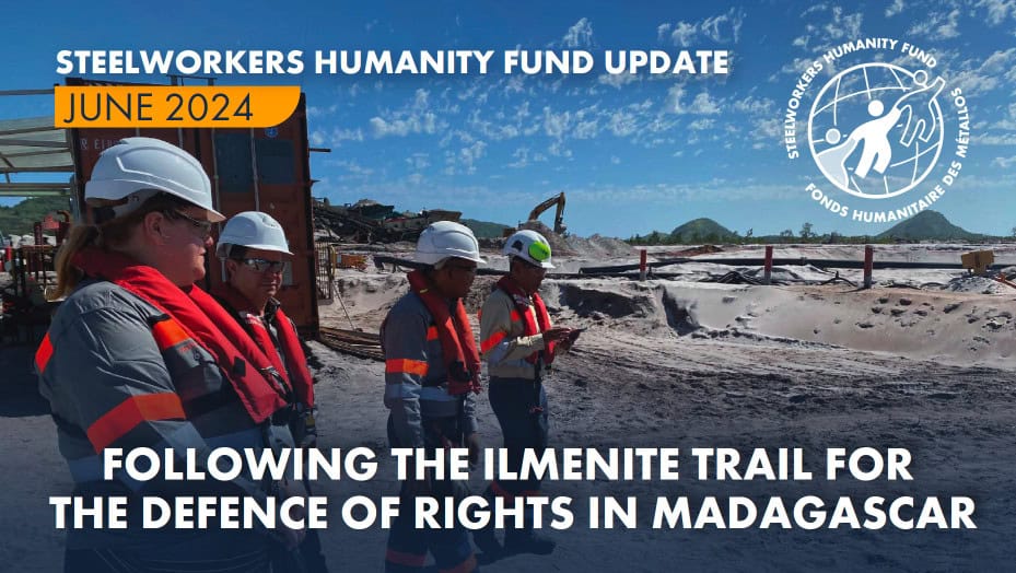 A photo of four people wearing satefy gear and walking in a mine. There are mining equipments in the background spread around and large sandy surface. There is text on the top of the photo saying STEELWORKERS HUMANITY FUND UPDATE - June 2024. More text at the very bottom saying: FOLLOWING THE ILMENITE TRAIL FOR THE DEFENCE OF RIGHTS IN MADAGASCAR