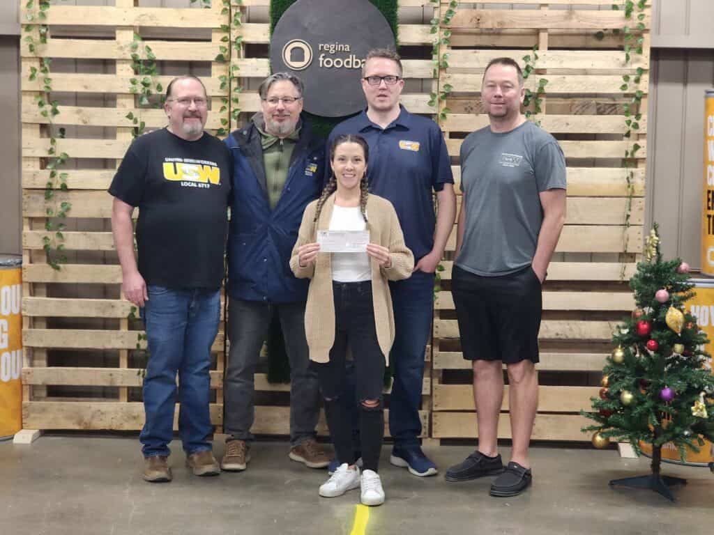 Four USW members taking a photo with a food bank representative. The rep is holding a cheque.