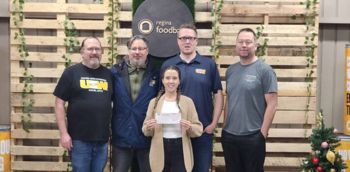 Four USW members taking a photo with a food bank representative. The rep is holding a cheque.