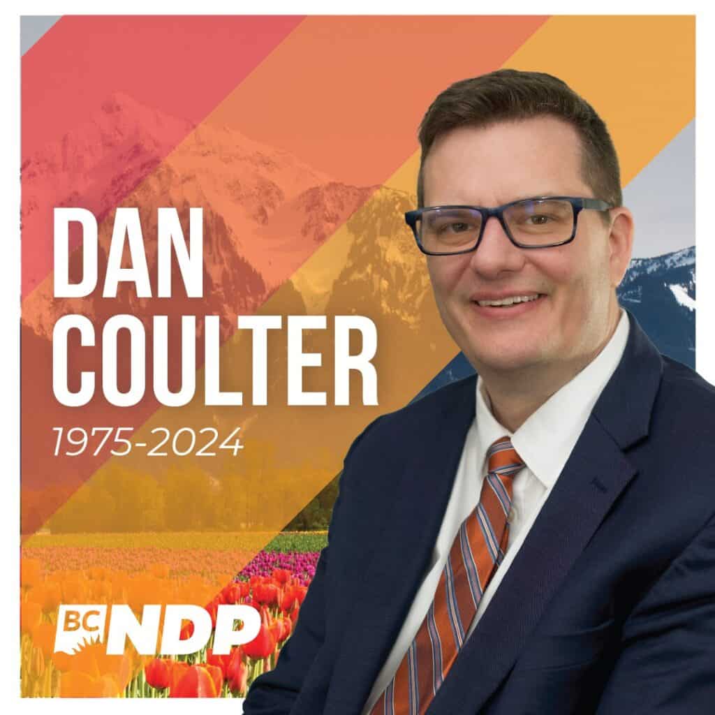 Man in suit with tie. Orange stripes in background with mountain scenery with the BC NDP logo