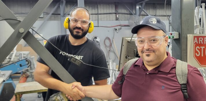 2 people standing in a workplace and shaking hands