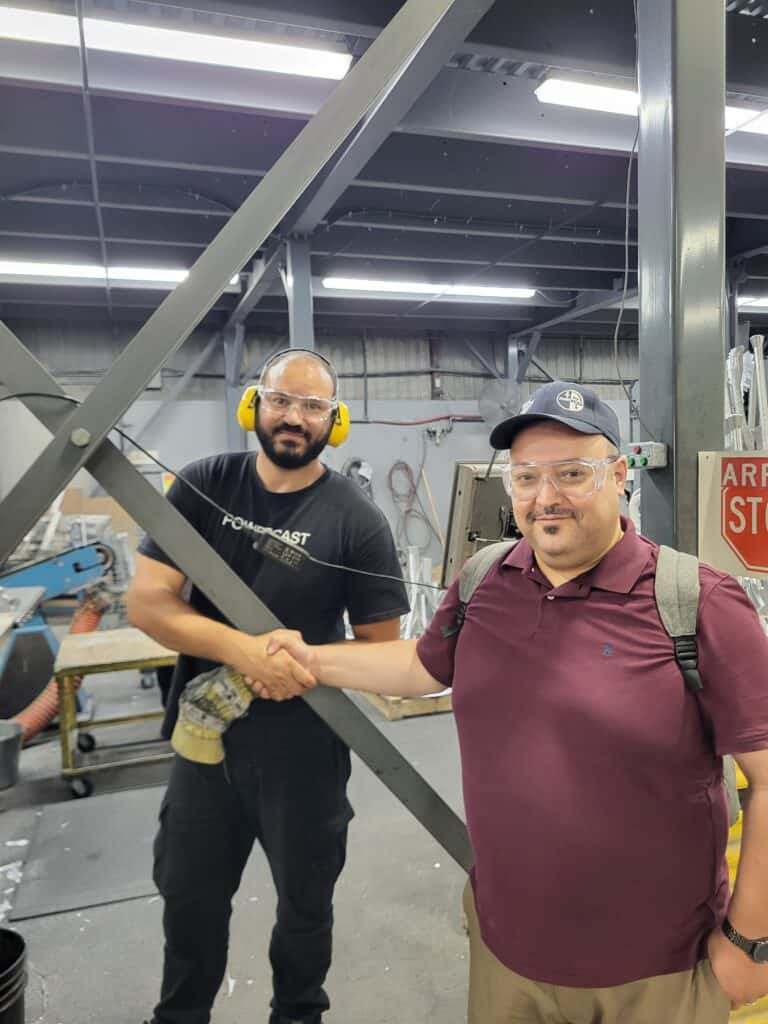 2 people standing in a workplace and shaking hands