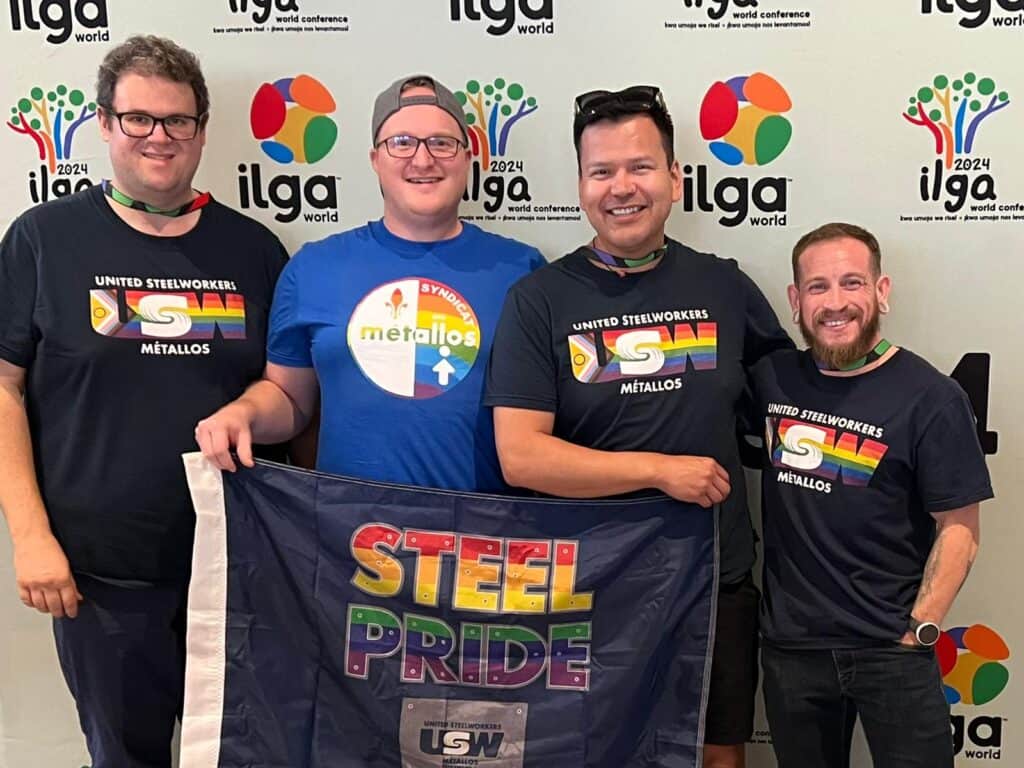 four people standing with the pride flag