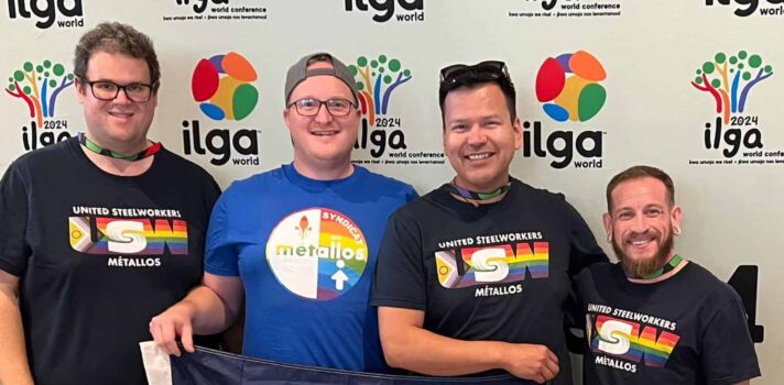 four people standing with the pride flag