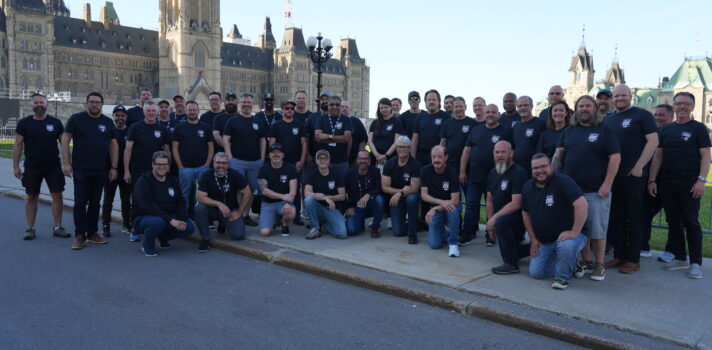 group of people standing in front of the parliament hill wearing bleu t-shirts