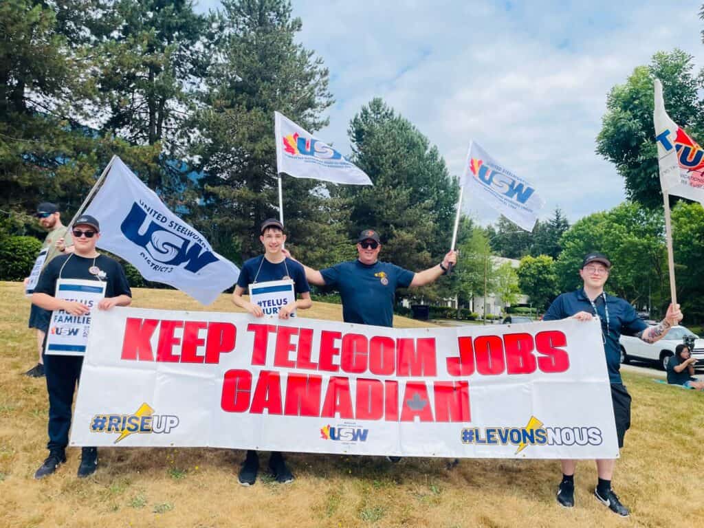 People standing outside, holding a sign that says, "Keep telecom jobs Canadian!"