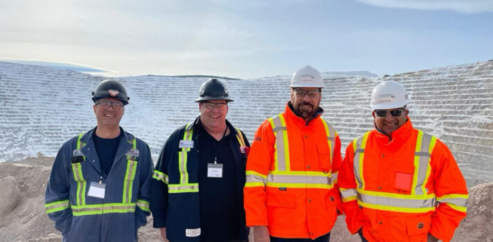 Four people in safety gear and hard hats smiling.