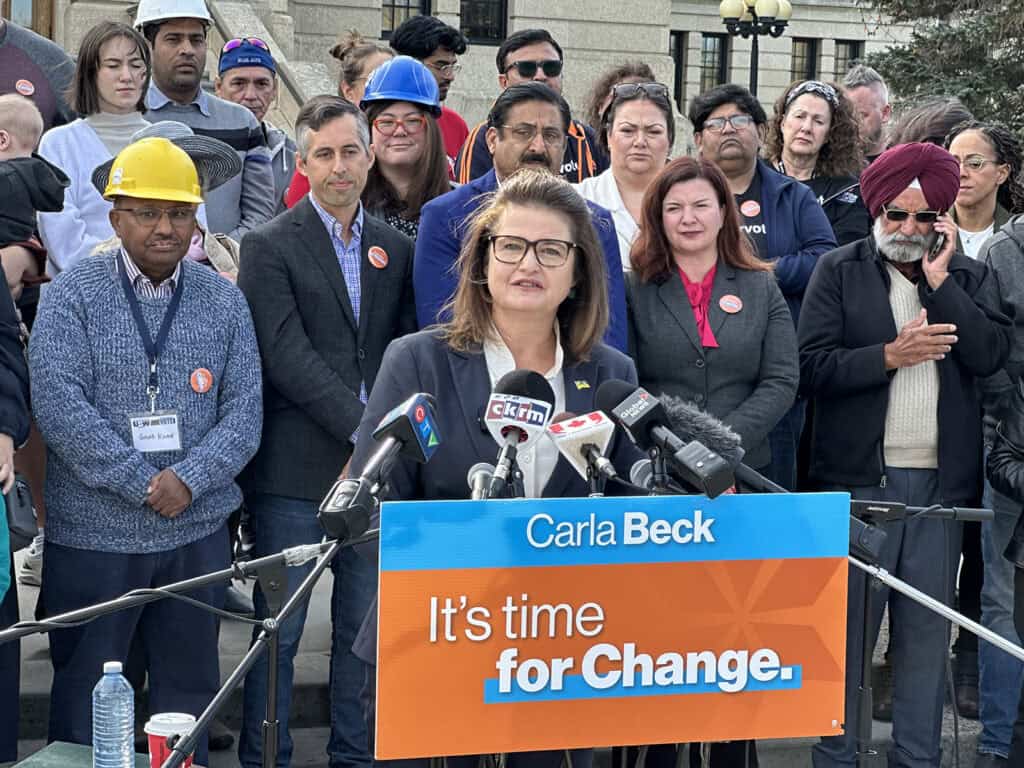 Carla Beck speaking at a microphone