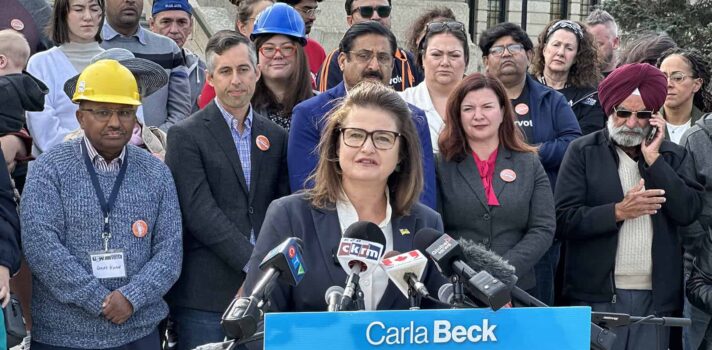 Carla Beck speaking at a microphone