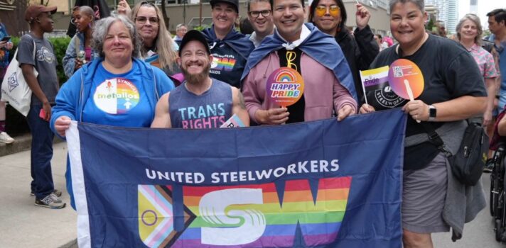 four people standing beside each other holding bleu flag with the Rainbow community logo