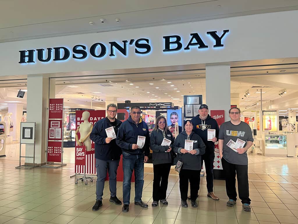 6 people holding flyers outside the Hudson's Bay store