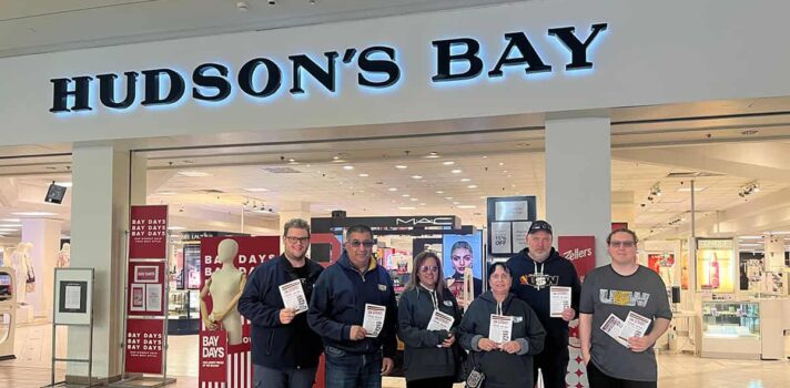 6 people holding flyers outside the Hudson's Bay store