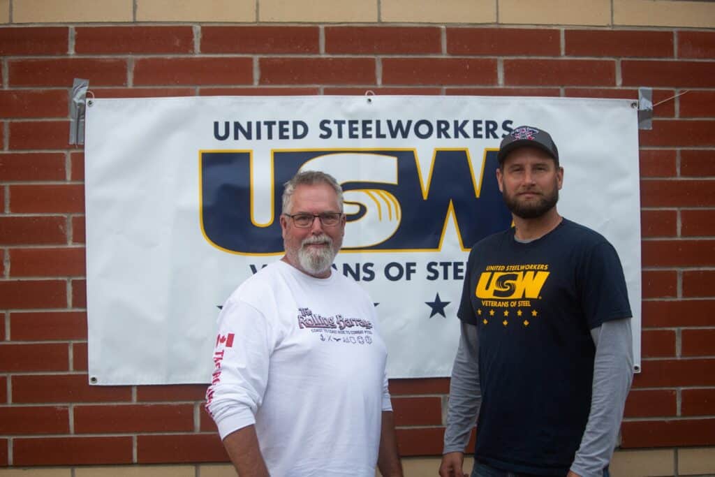 Steelworkers union members standing in front of a USW banner.