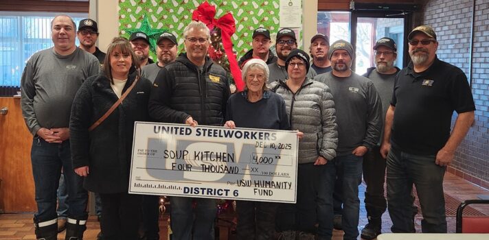 A group of people posing for the camera and hold a board.