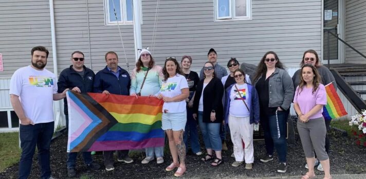 A group of people holding pride flag in from a building