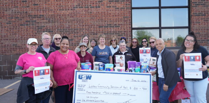 A group of people holding a a cheque behind a building.