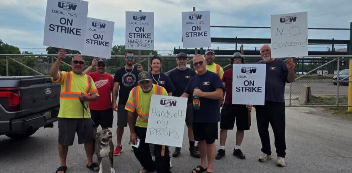A group of people holding a sign in front of a building.